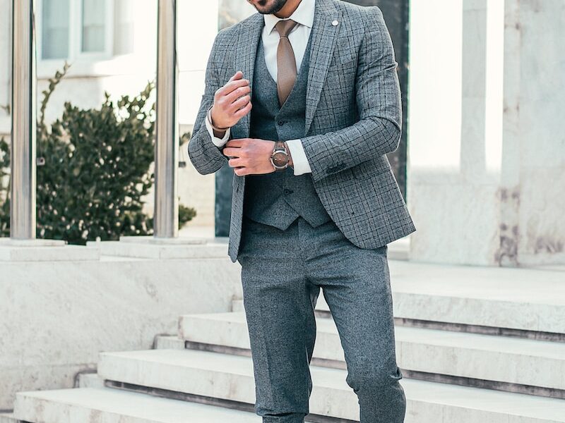 man in gray suit jacket and black pants standing on white staircase