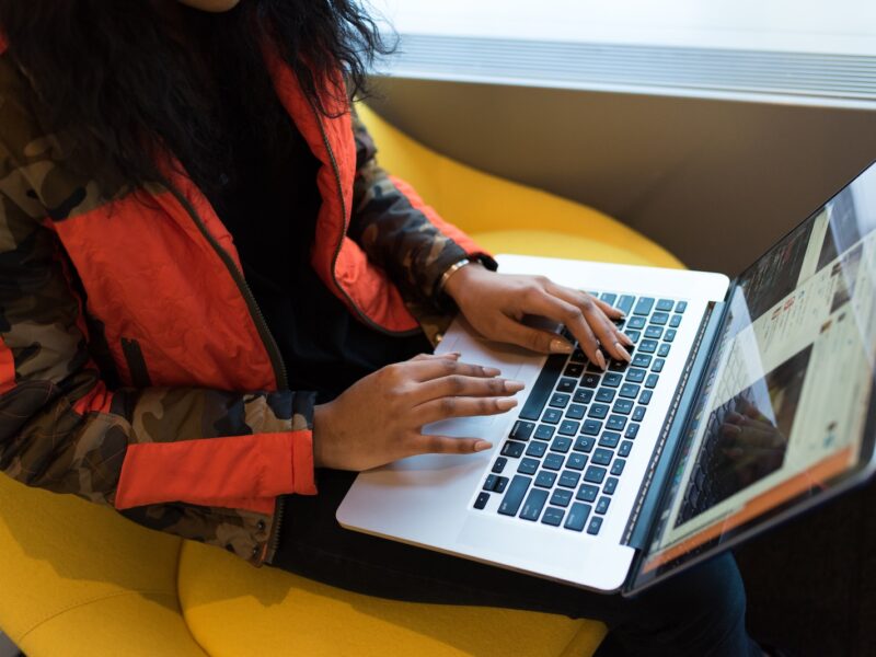 woman in red and black jacket using MacBook Pro