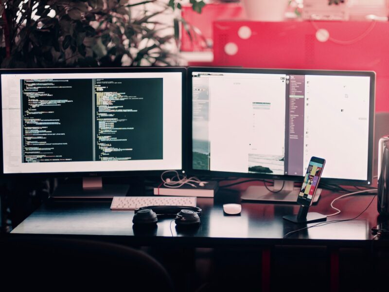 two black computer monitors on black table