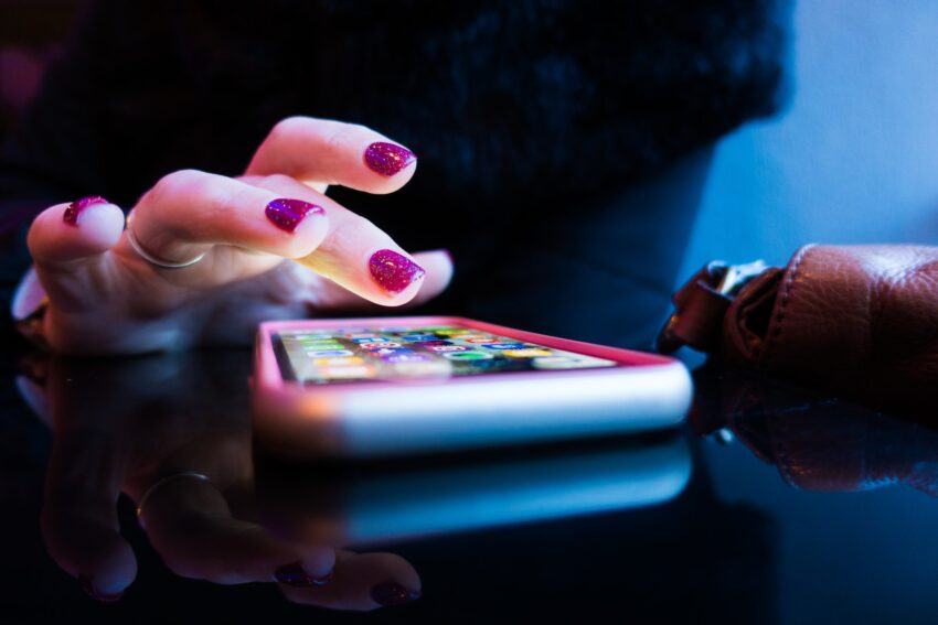 person using black smartphone with gray and pink case