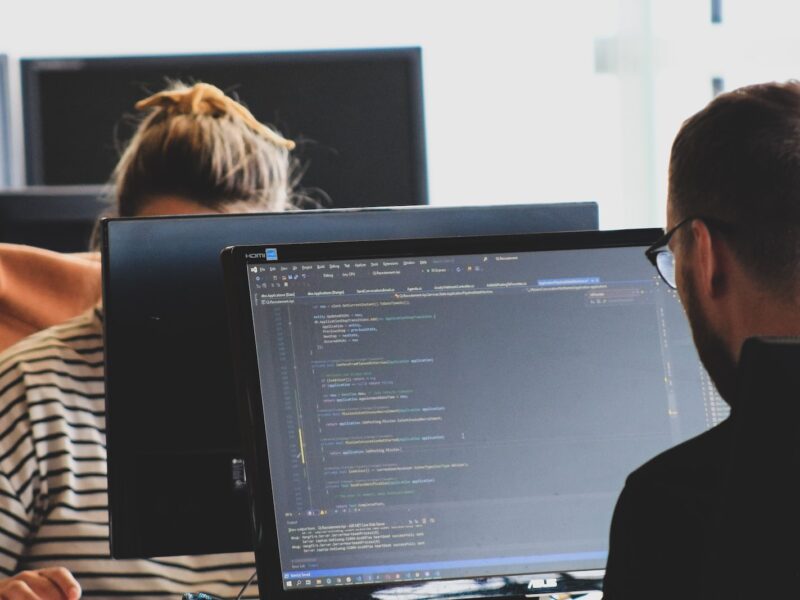 woman in black shirt sitting beside black flat screen computer monitor