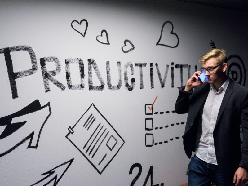 man holding smartphone looking at productivity wall decor