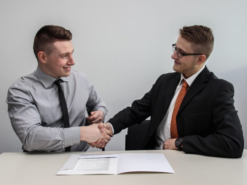 two men facing each other while shake hands and smiling