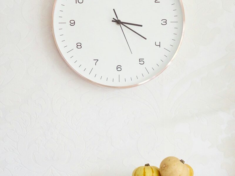 two pumpkins on table below wall clock