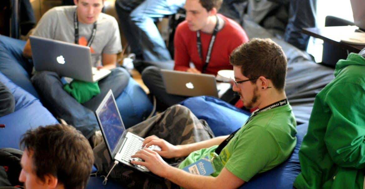 man sitting on blue bean bag usinglaptop