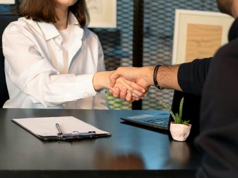 a man and a woman shaking hands in front of a laptop