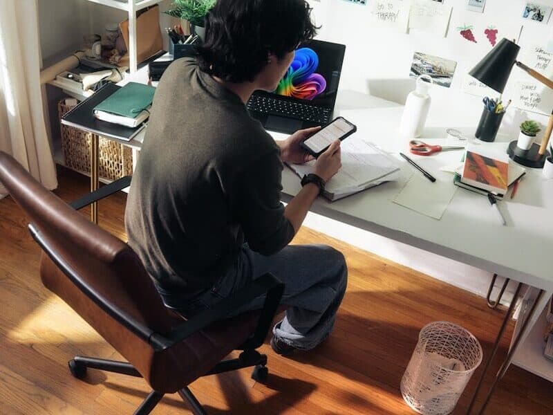 Man working at desk with laptop and phone.